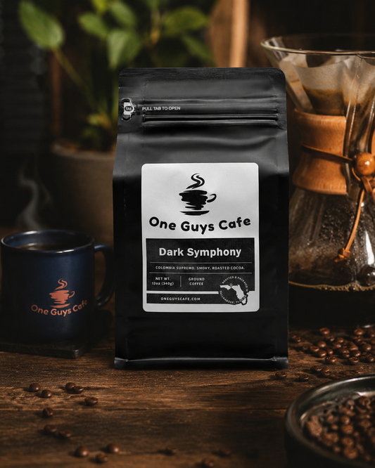 One Guys Cafe Dark Symphony dark roast coffee bag with pour-over brewer, branded mug, and coffee beans on a wood table.