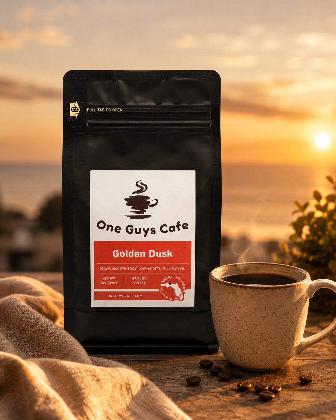 One Guys Cafe Golden Dusk decaf coffee bag beside a steaming mug at sunrise with warm golden light.
